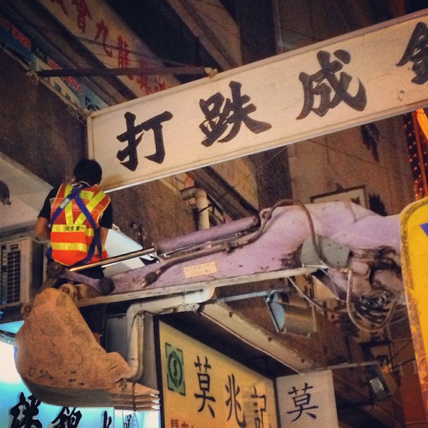 A #worker rides an #excavator to fix a #signboard. #hongkong #hk #hkig