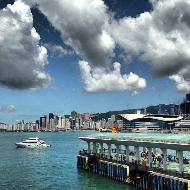 A #boat floats just ahead of the #pier on #victoriaharbour while fluff ball clouds drift lazily across the sky. #hongkong #hk #hkig #harbour