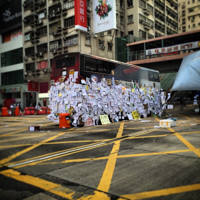7.40am on day 6 of #OccupyHK in #Mongkok and the junction of #MongkokRoad and #NathanRoad remains occupied. The stranded #bus has become a message board where the public come to post their words of encouragement. The amount of messages posted has made it look as though the bus is wearing a skirt. #HongKong #hk #hkig