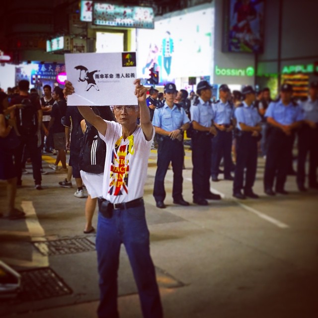 A lone man holds up a sign for the #umbrellarevolution while the #police hold the line behind him. #OccupyHK #Mongkok #HongKong #hk #hkig