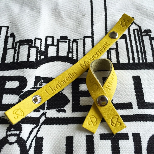 From the #UmbrellaMovement - button up #leather #yellowribbons. There's a workshop at #OccupyHK #Admiralty where you can make your own #OccupyCentral #yellowribbon. It's different from the others as you make it yourself and it's made with a snap fastener, so you can fold and unfold the ribbon. The other ribbons are fixed. The volunteers guide you in making holes in the leather and putting in the fasteners. #HongKong #hk #hkig