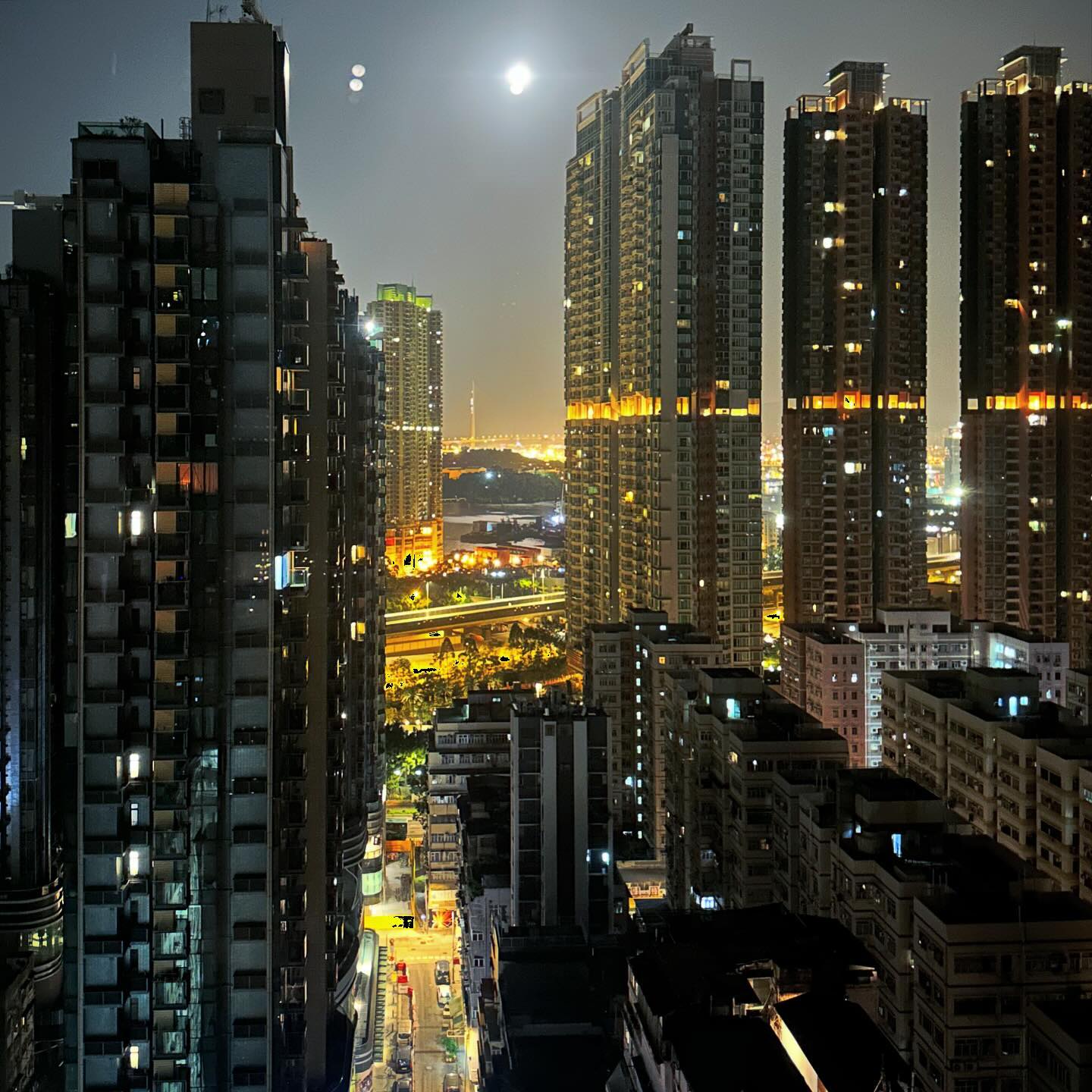 cityscape in TaiKokTsui, Kowloon. A lensflare moon over the city at night. hongkong hk hkig