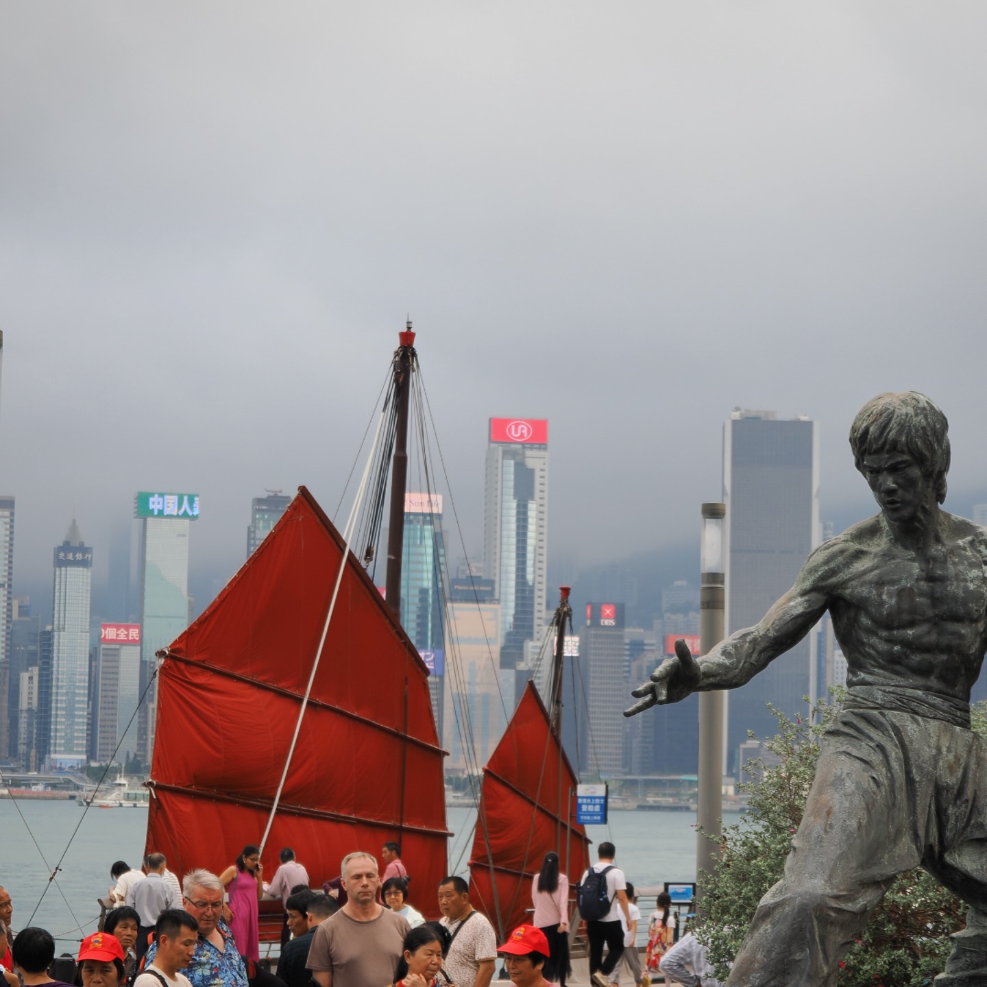 Quintessentially Hong Kong – view from the Avenue of Stars in Tsim Sha Tsui. A tourist junk, the Hong Kong skyline and Bruce Lee on Victoria Harbour. hongkong hk hkig brucelee tsimshatsui avenueofstars