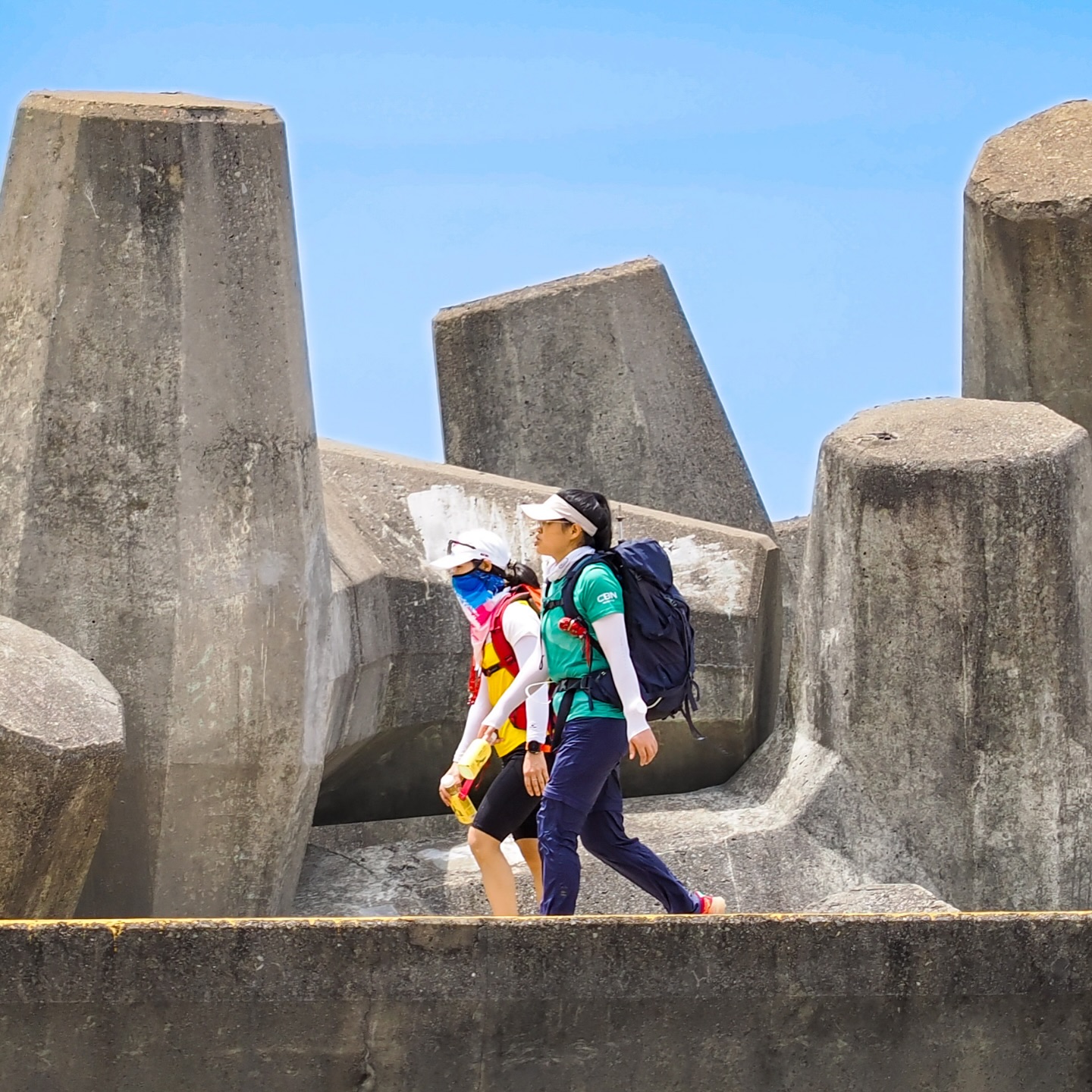 Hikers walking past the Dolos along the High Island Reservoir East Dam in Sai Kung Country Park. hongkong hk saikung hike highislandreservoir dam dolos geopark